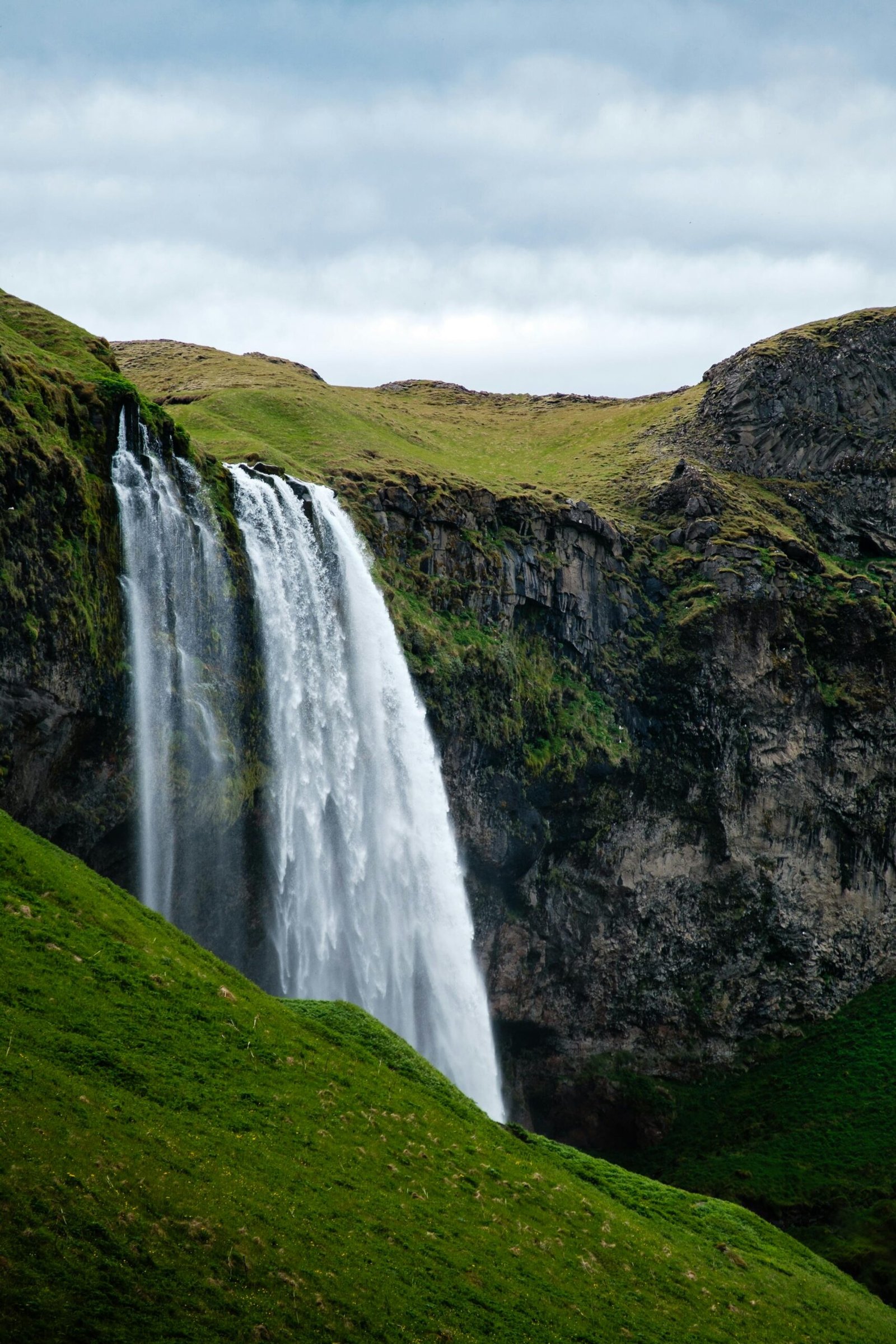Stunning view of Seljalandsfoss waterfall cascading down a lush green hill in Iceland.