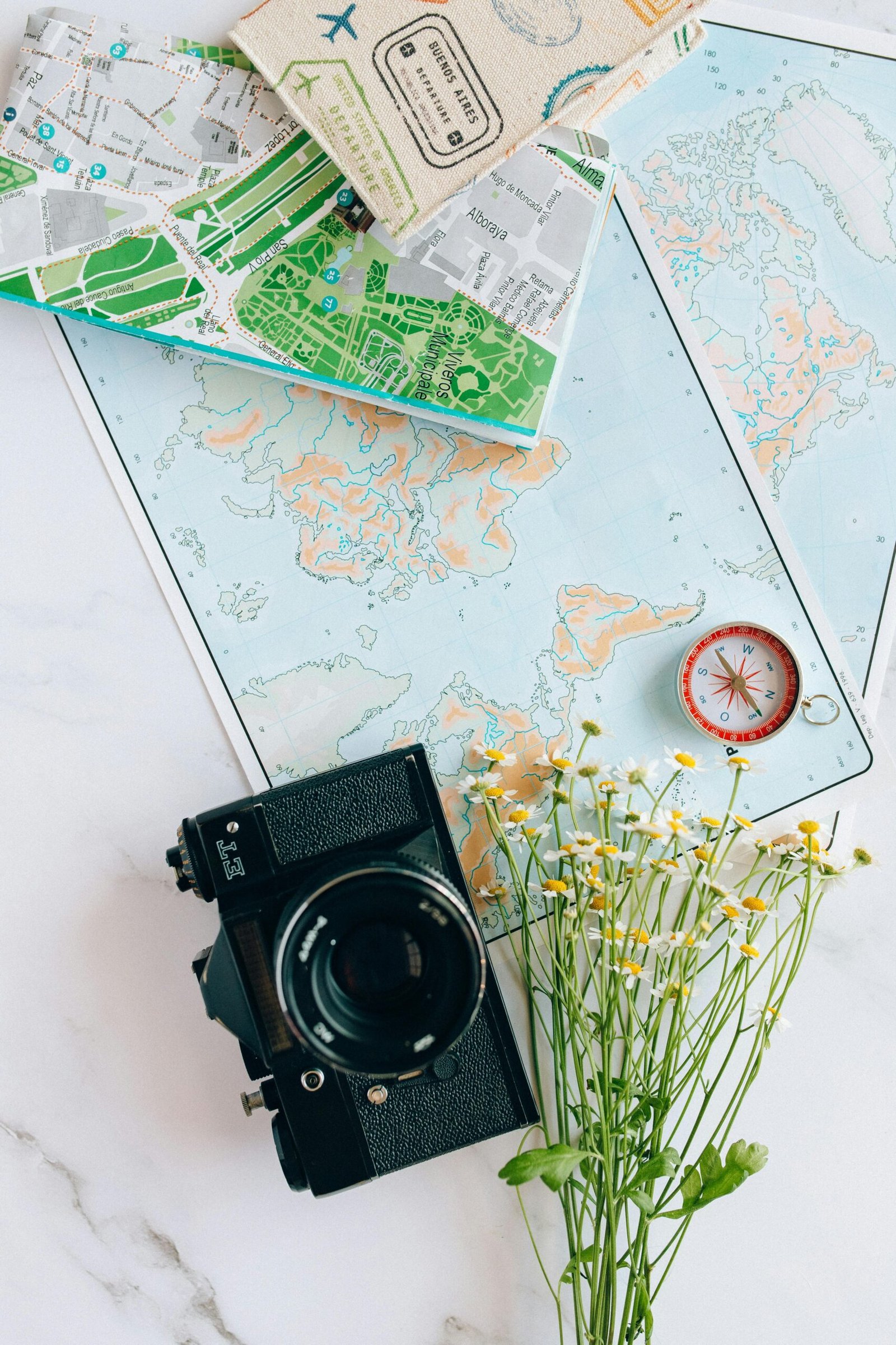 A nostalgic flatlay of a camera, maps, and compass—perfect for travel enthusiasts.